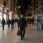 Akşam saatlerinde iyi aydınlatılmış şehir yürüyüş yolunda güvenli biçimde yürüyen yetişkin kişi